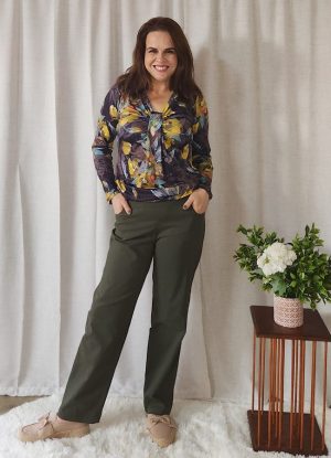 Woman wearing a floral top and olive green Bengaline Relaxed Fit Pants, standing and smiling.