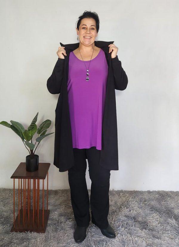 Woman wearing the Zelda Cosy Collar Pocket Cardigan in black cosy spandex knit, showing off the soft collar. Styled over a purple top with black pants and boots – custom-made for autumn and winter in South Africa.