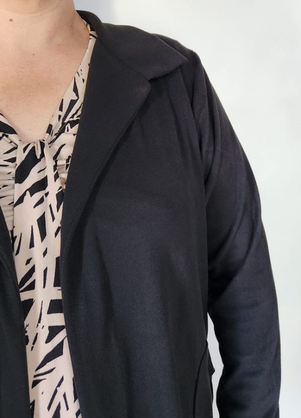 Close-up of the Zelda Cosy Collar Pocket Cardigan collar in black cosy spandex knit, styled over a patterned neutral blouse. Shows the refined neckline and soft texture – custom-made for South African women.