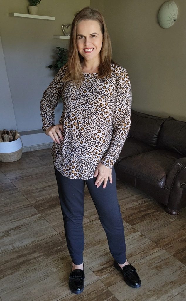 Smiling woman showcasing a casual-chic winter look by J&S Creations, featuring a long sleeve leopard print top in soft DTY brush knit paired with comfortable black Terry Knit pants. A custom-made, stylish outfit designed for South African women who value both fashion and comfort, available in sizes Small to 6XL.