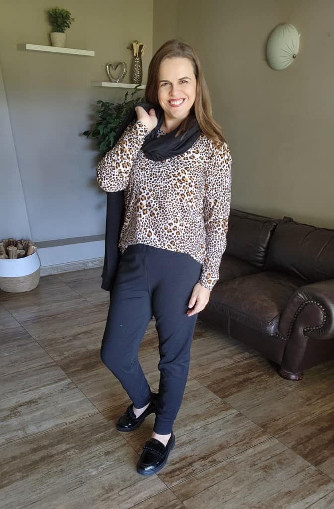 Smiling woman showcasing a casual-chic winter look by J&S Creations, featuring a long sleeve leopard print top in soft DTY brush knit paired with comfortable black Terry Knit pants. A custom-made, stylish outfit designed for South African women who value both fashion and comfort, available in sizes Small to 6XL.