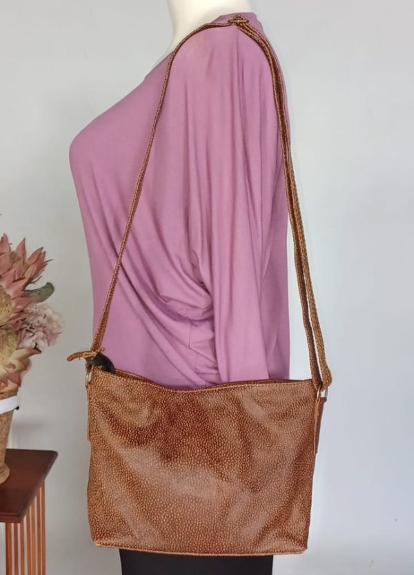 Light tan Rosy Genuine Leather Handbag with pebbled finish, shown on mannequin as a crossbody bag. Sleek and compact South African design, 25cm wide.